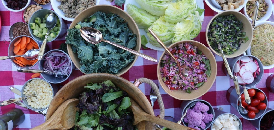 Bowls of colorful salad on a red/white tablecloth.