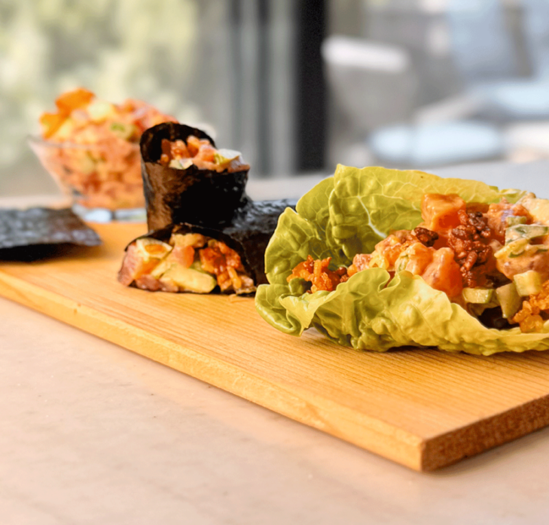 Spicy tuna tartare served in lettuce cups and seaweed wraps on a wooden board