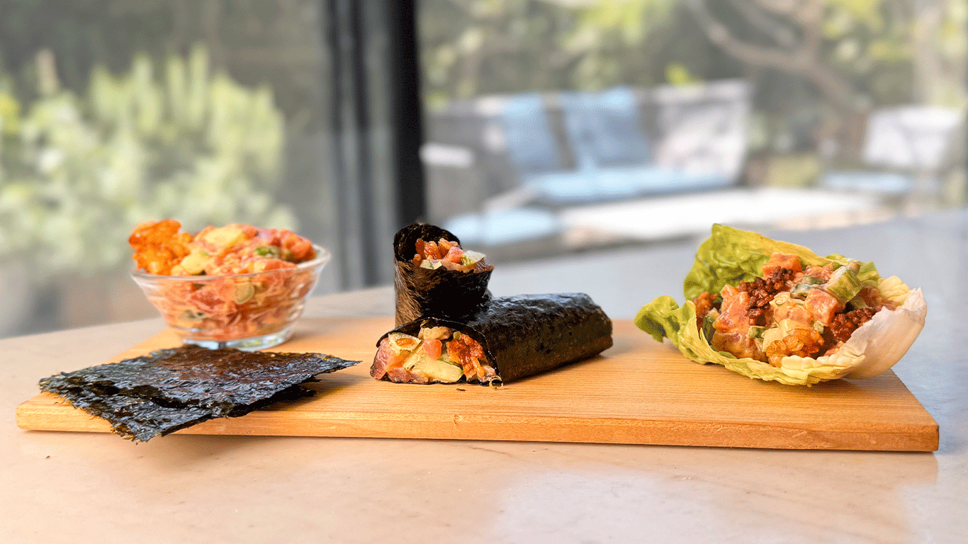 Spicy tuna tartare served in a glass bowl, wrapped in nori, and in a lettuce cup on a wooden board