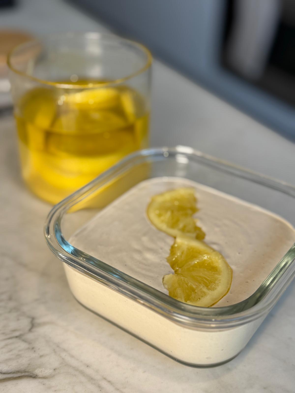 Creamy store-bought tahini topped with lemon slices in a glass container after fixing chunky consistency