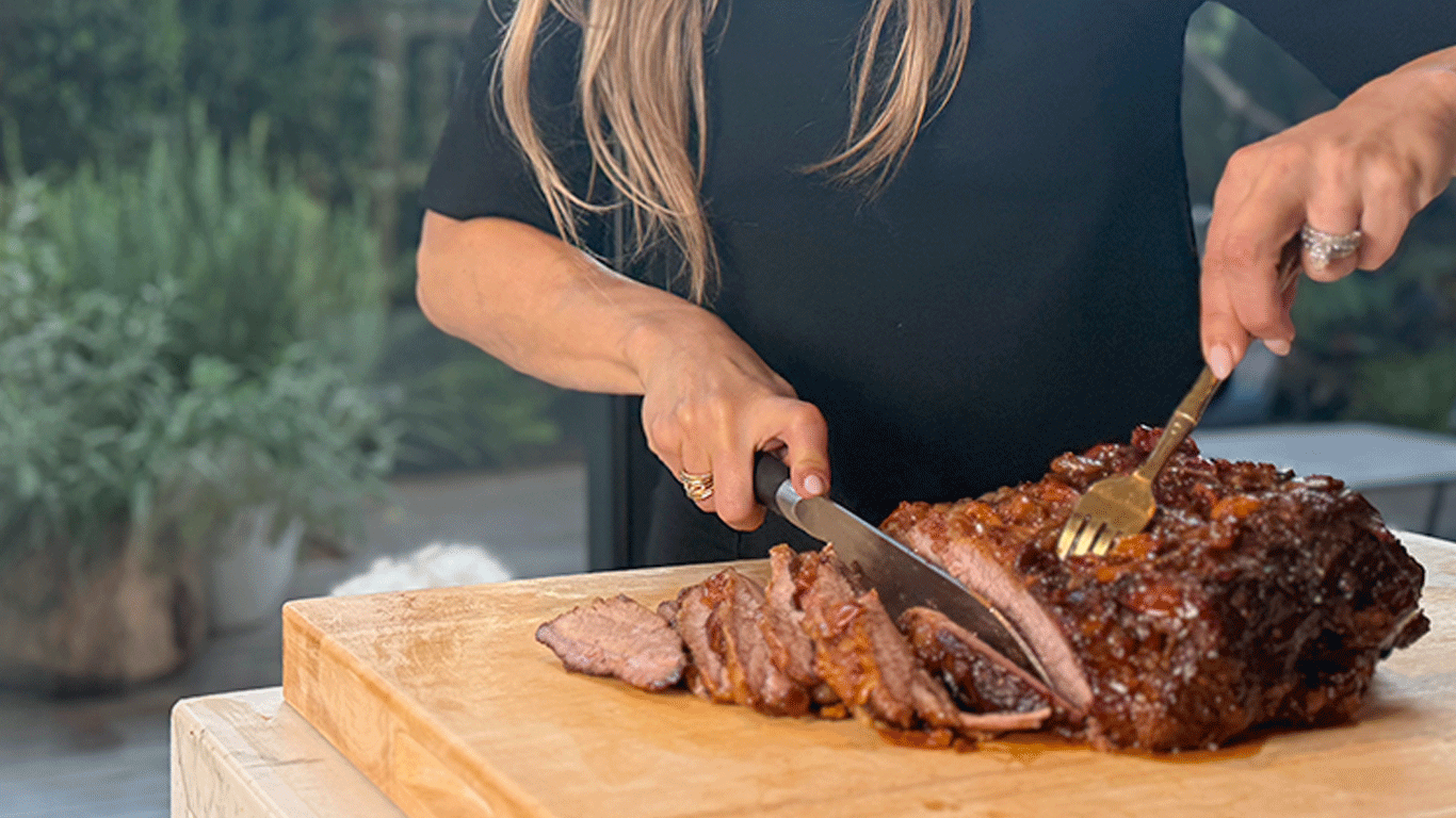 Nealy slicing a juicy, slow-roasted brisket on a wooden cutting board