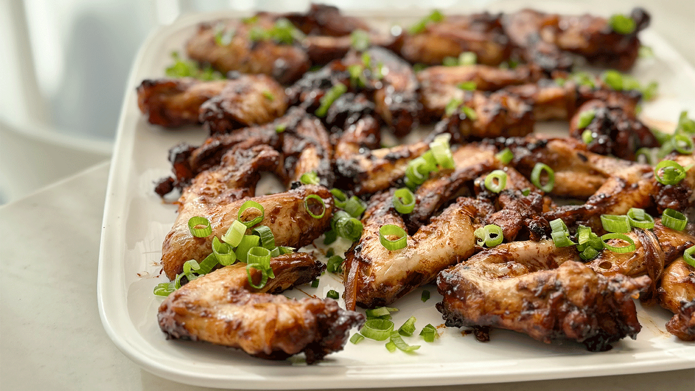 A platter of roasted Adobo Chicken Wings garnished with sliced green onions